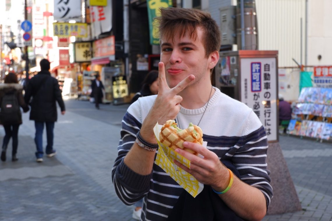 Jayden Thomas holds up a peace sign while eating food.